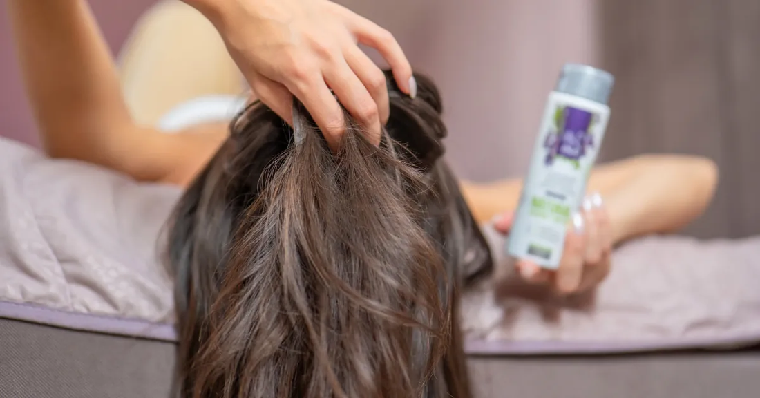 Mulher a passar os dedos pelo cabelo devido a comichão no couro cabeludo sem caspa, ao lado da Água de Sálvia Orgânica Hydrolina