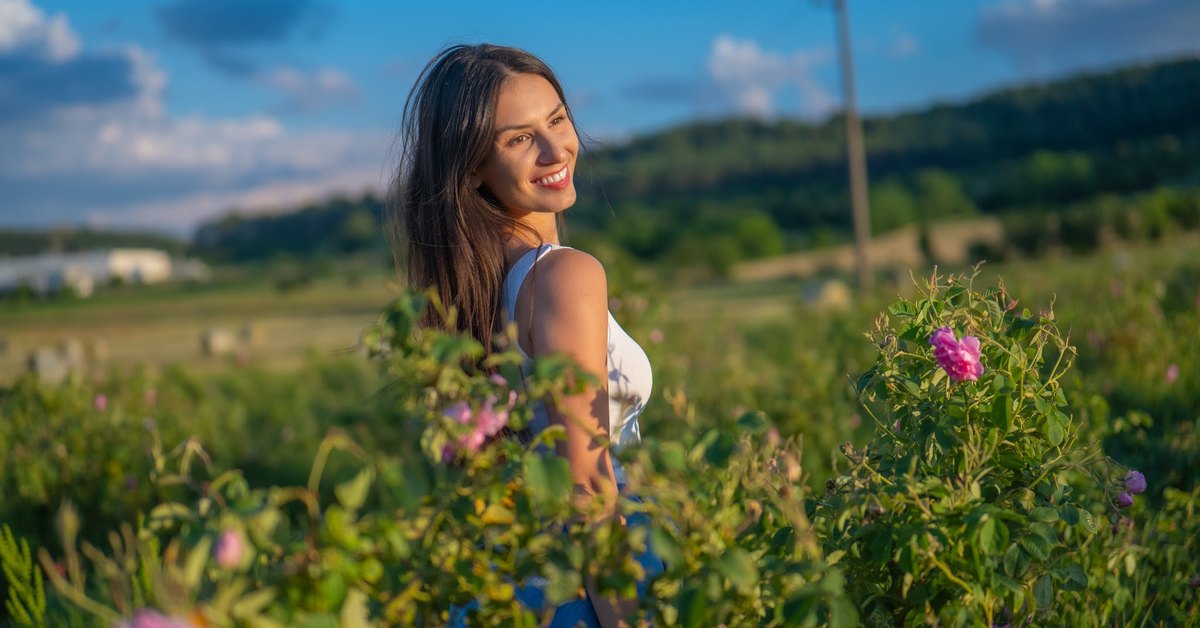 Mulher num campo de rosas em flor no Vale das Rosas búlgaro